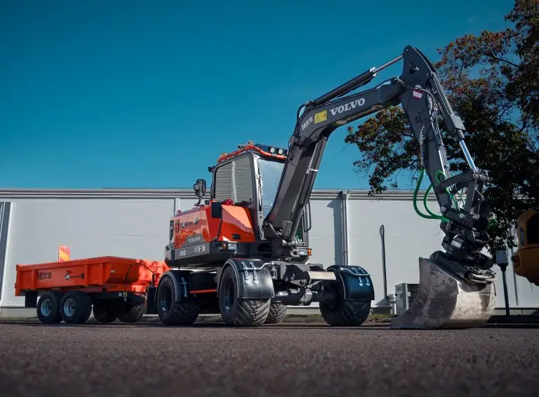 Orange MaserFrakt grävmaskin med vagn på en parkering