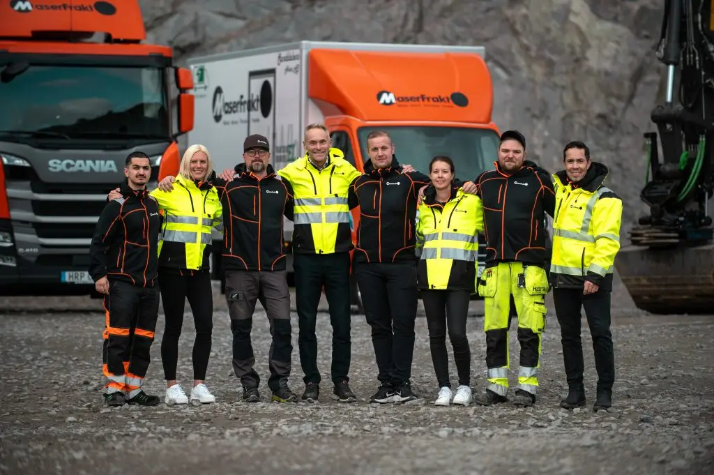 MaserFrakt personal, chaufförer och delägare i en bergtäkt med lastbilar i bakgrunden